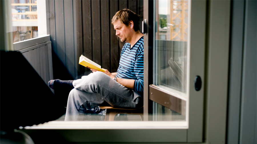 En person läser en bok på balkongen.