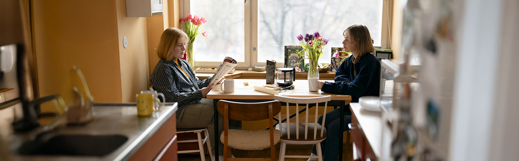 Two people are sitting in the kitchen.