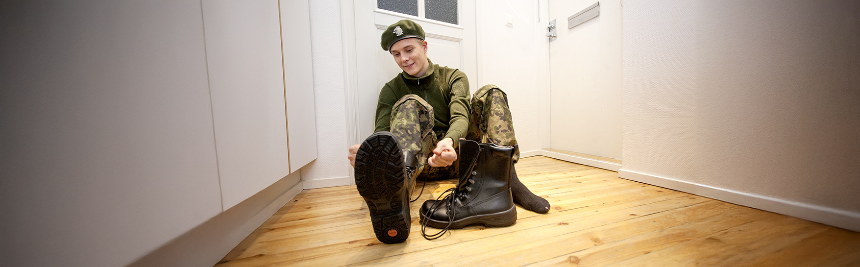 A person in military service is putting on shoes.