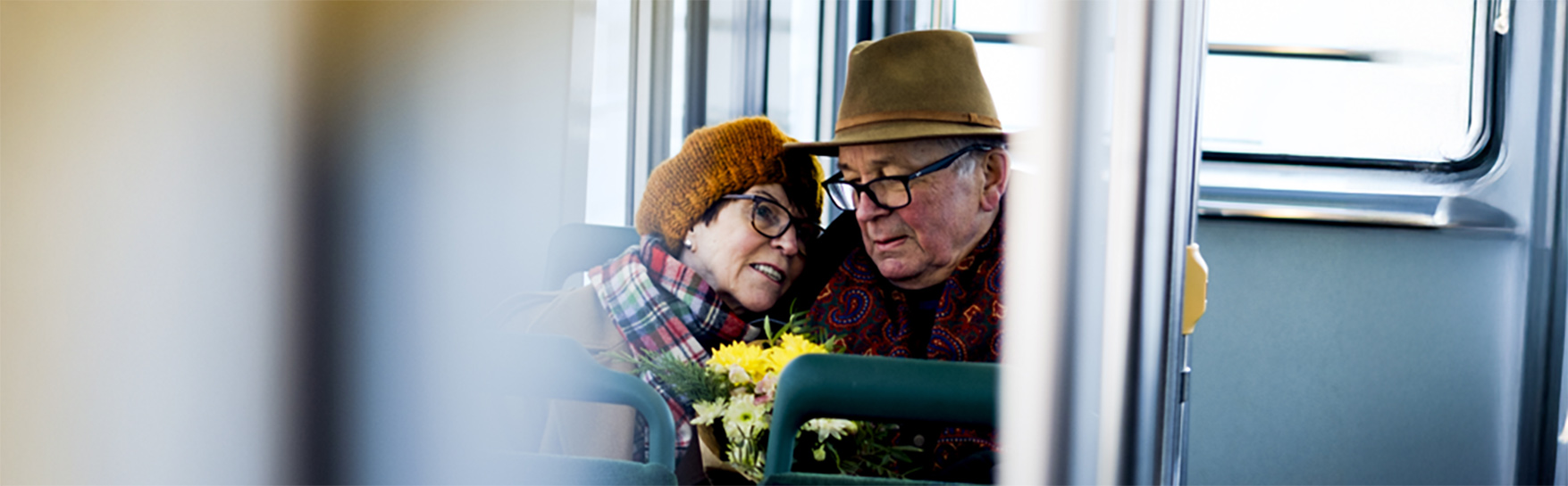 An elderly woman and man are sitting on a bus.