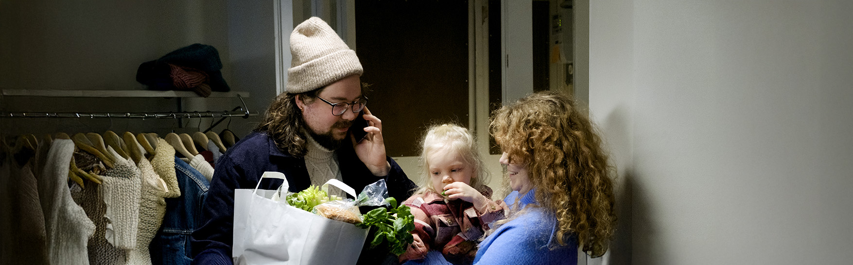 Two adults and a small child in the hallway. The child is in the arms of one of the adults.