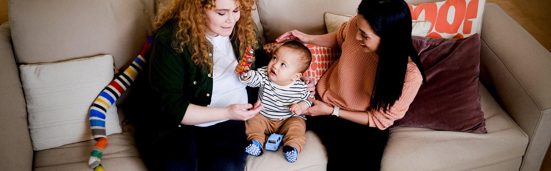 Kaksi naista ja pieni lapsi istuvat sohvalla.