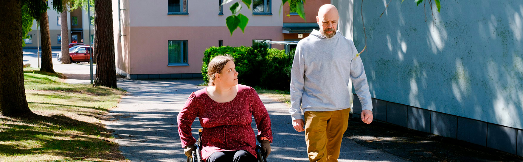 En kvinna i rullstol och en man utomhus.