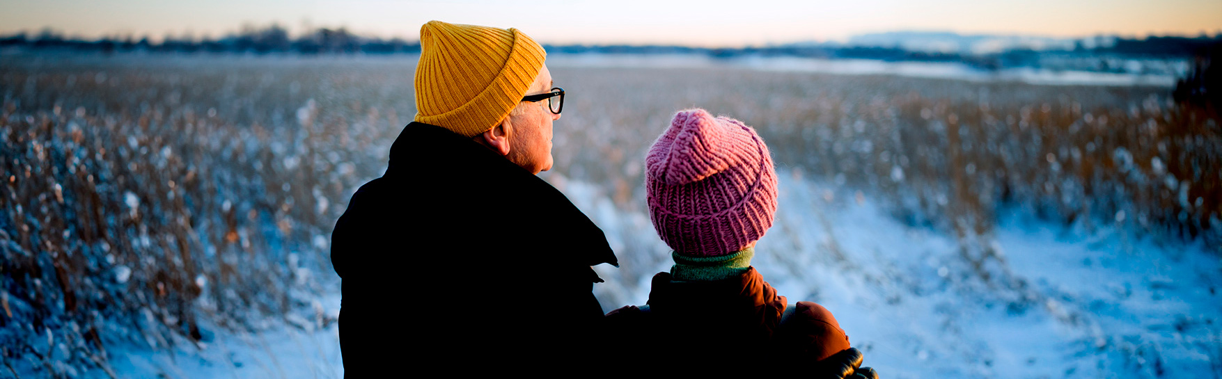 Two people are standing in a snowy field.
