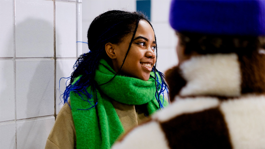 Two cheerful youths stand facing each other at the railway station.