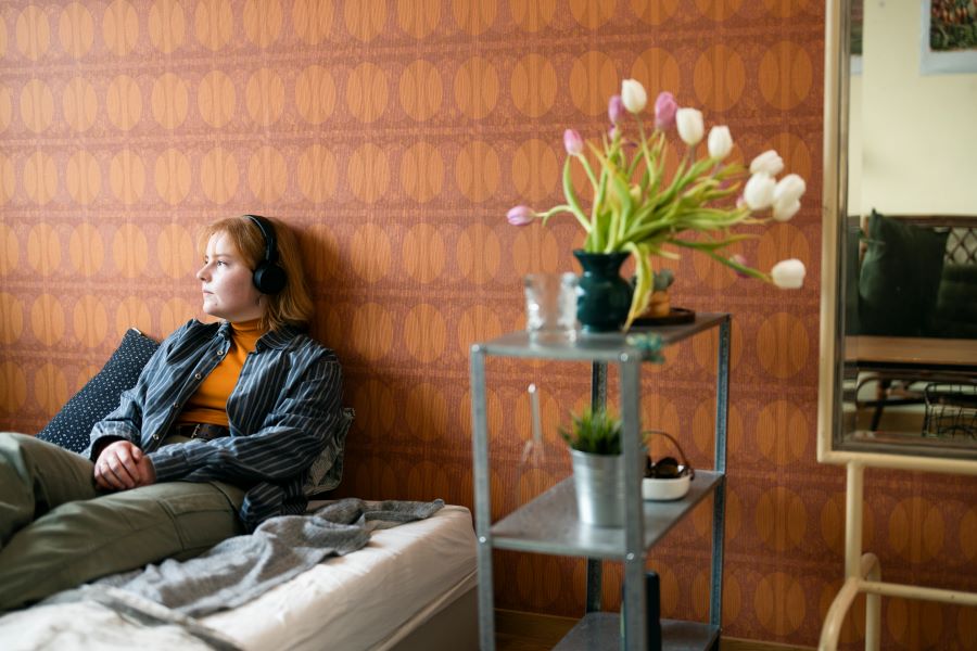 A young person is sitting on a bed and thinking.