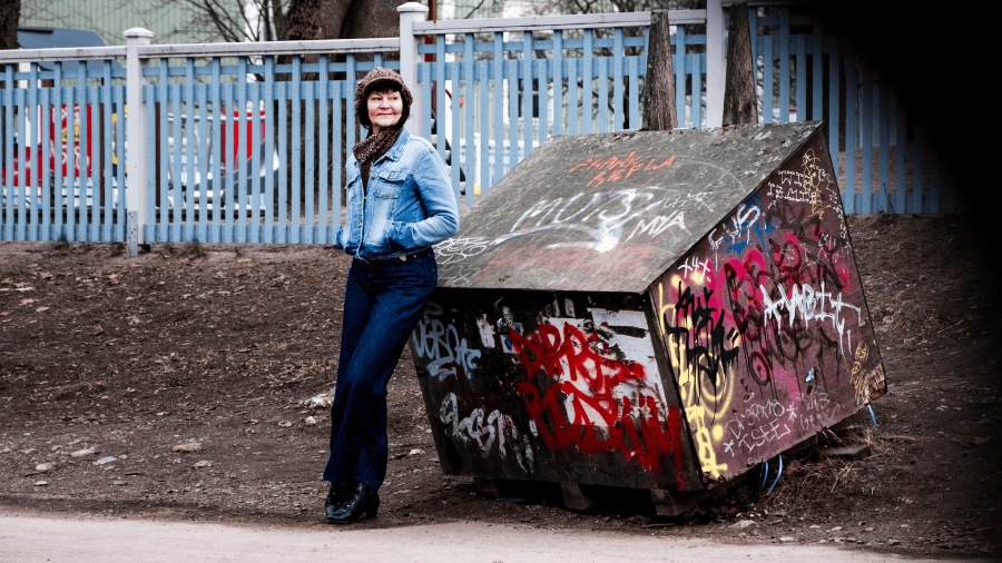 Henkilö seisoo ulkona graffitien peittämän rakenteen vieressä.